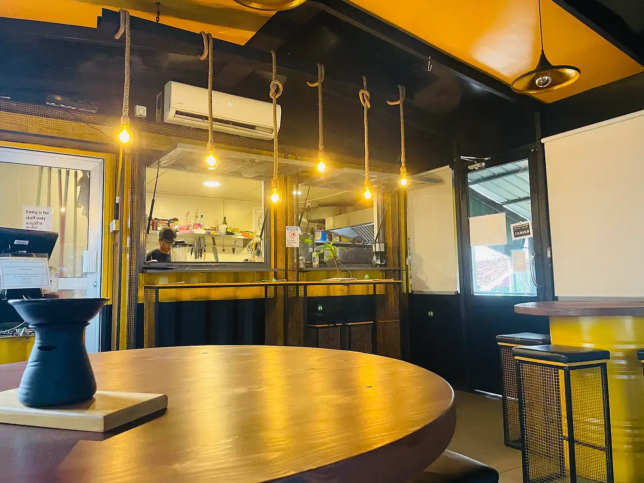 The Octa counter in Nugegoda with hanging Edison bulbs, yellow bar stools and a round wooden table