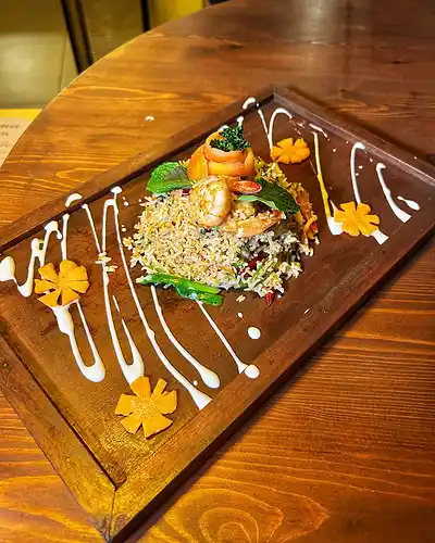 Fried rice plated with flowers and sauce on a wooden board