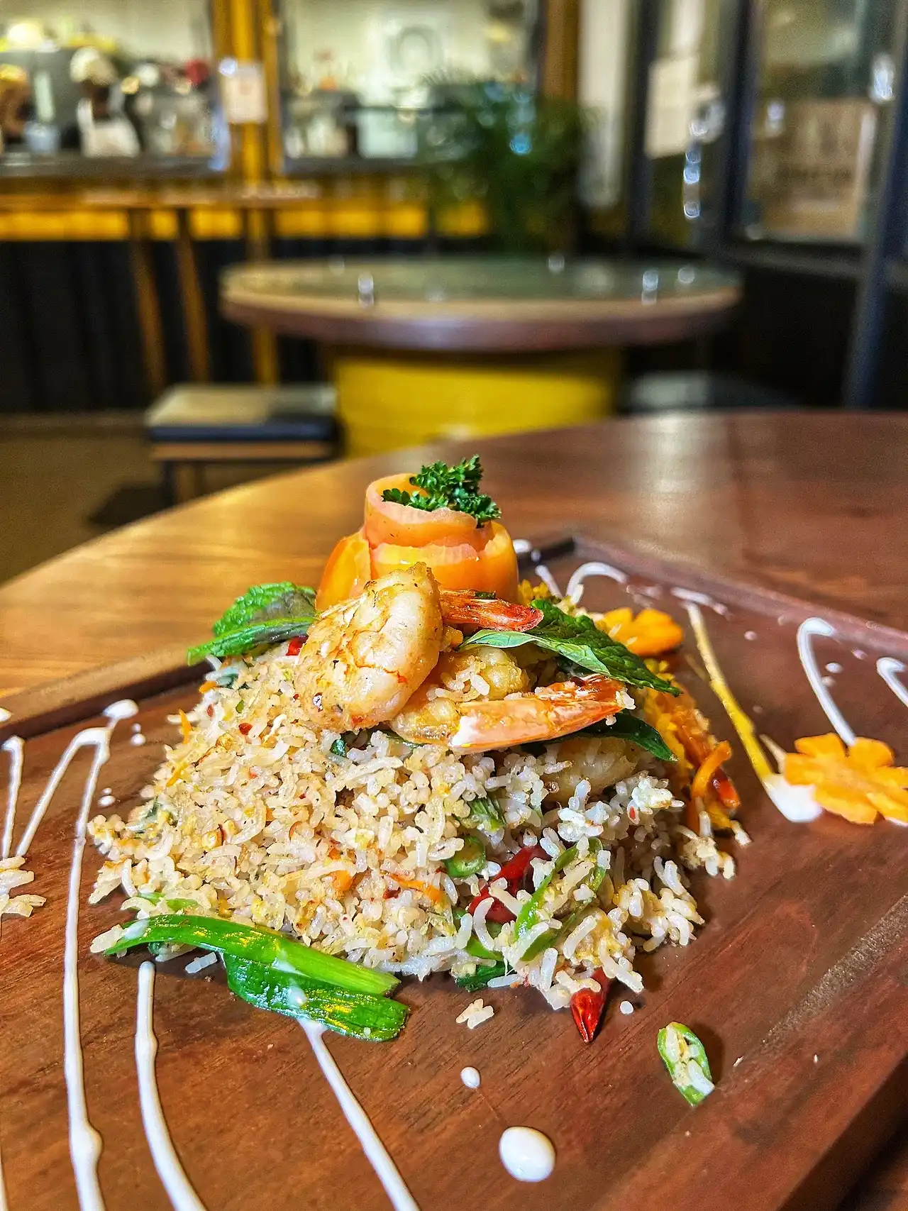 Basmati seafood fried rice topped with prawns on a wooden board