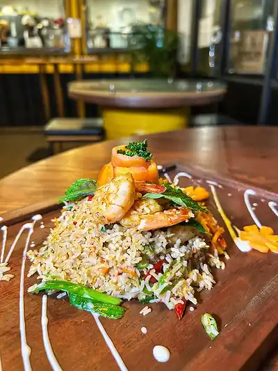 Basmati seafood fried rice topped with prawns on a wooden board