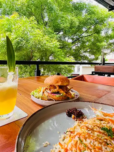 Burger, fresh juice and salad on the terrace at The Octa, with trees behind