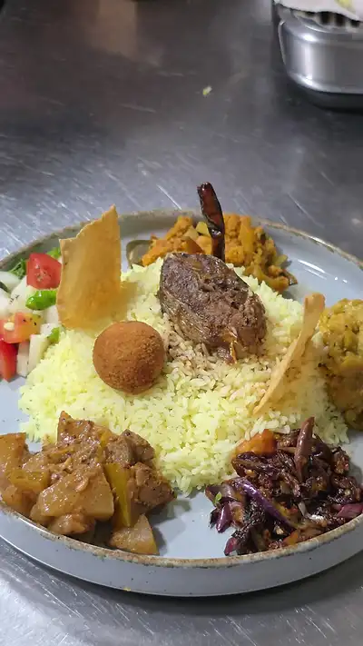 Yellow rice plate with frikkadel, curries, seeni sambol and papadam